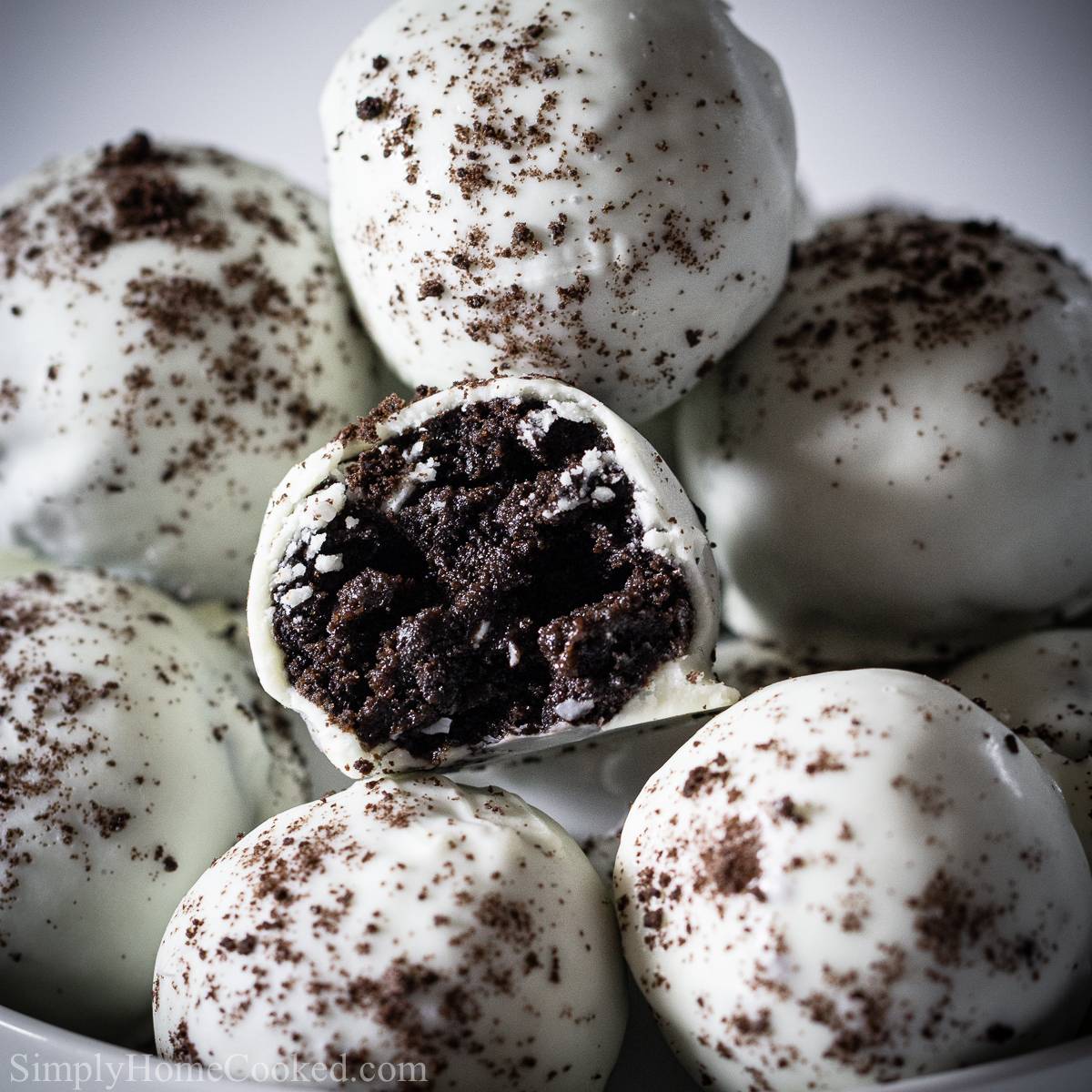 stack of oreo cake balls dipped in white chocolate with one cake ball bitten