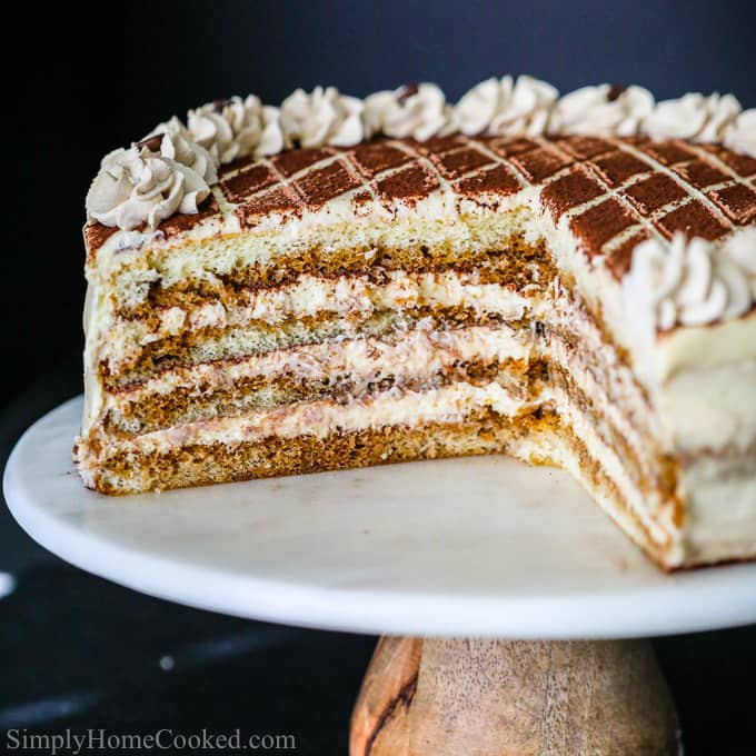 close up image of a layered tiramisu cake thats missing a slice