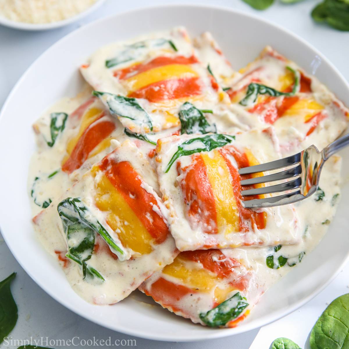 close up image of creamy lobster ravioli with spinach on top