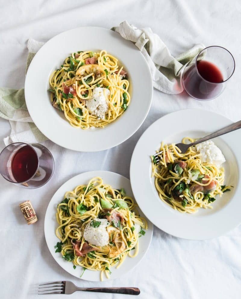 three round white plates with pasta near two glass cuups