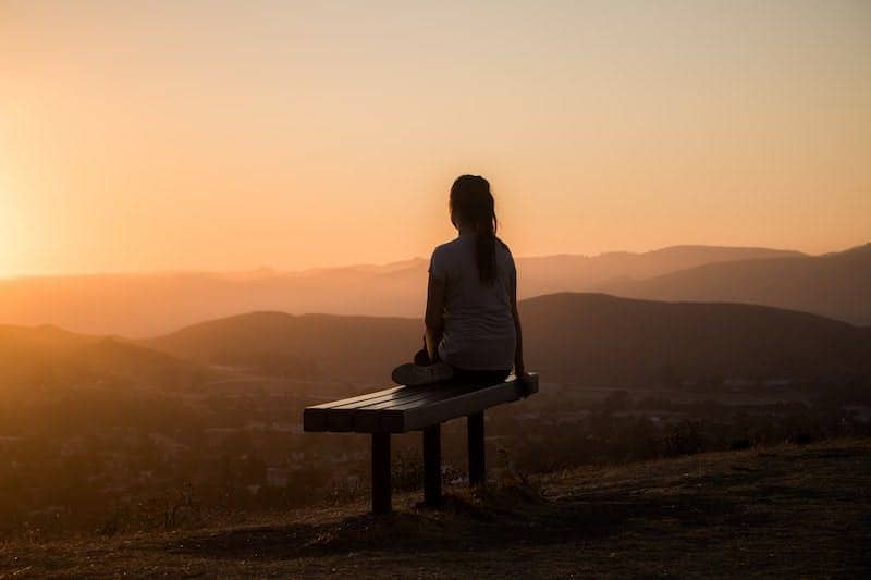 woman sitting on bench over viewing mountain