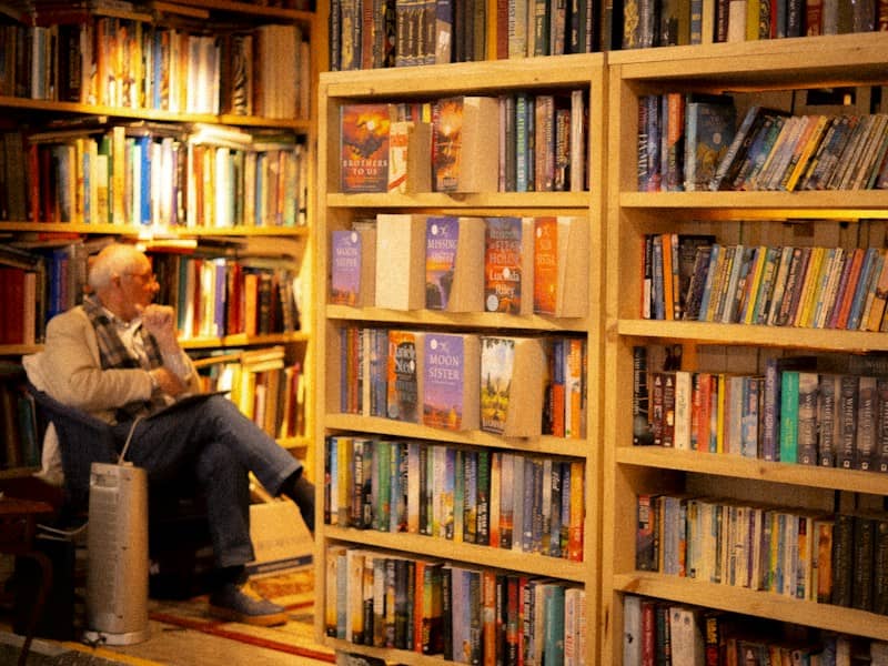 An elderly person sitting in a chair reading in a bookstore