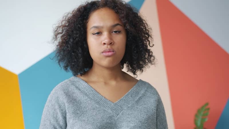 Young woman with curly hair against colorful wall