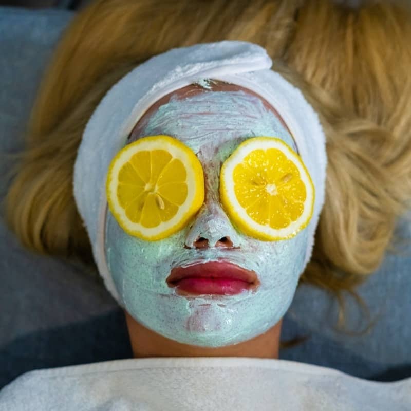 a woman with a towel on her head and two slices of lemon on her face
