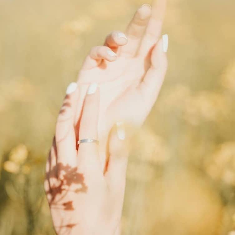 a woman holding her hand up in a field of flowers