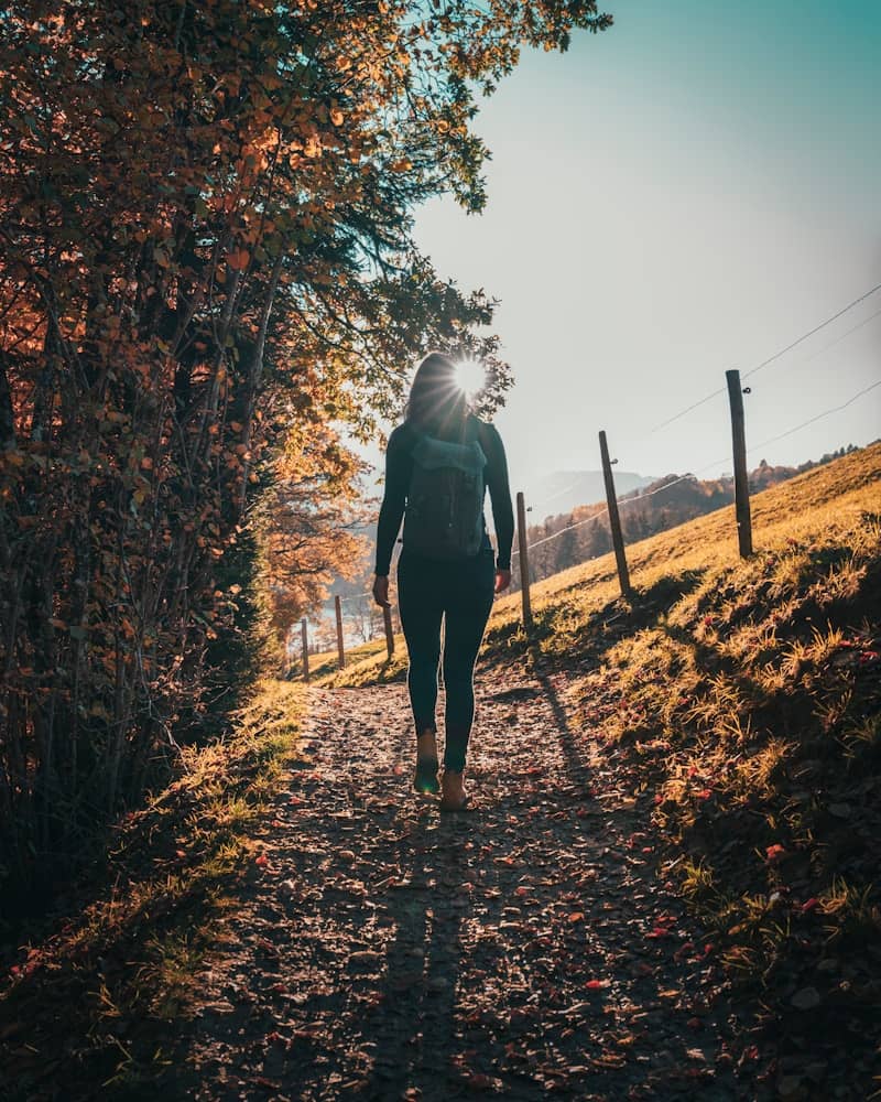 man in gray jacket walking on brown dried leaves during daytime