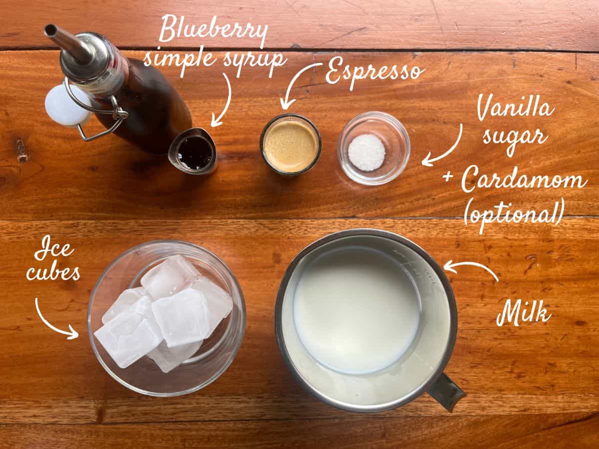 Ingredients for blueberry iced latte: ice cubes, blueberry simple syrup, espresso, vanilla sugar, cardamom (optional) and milk