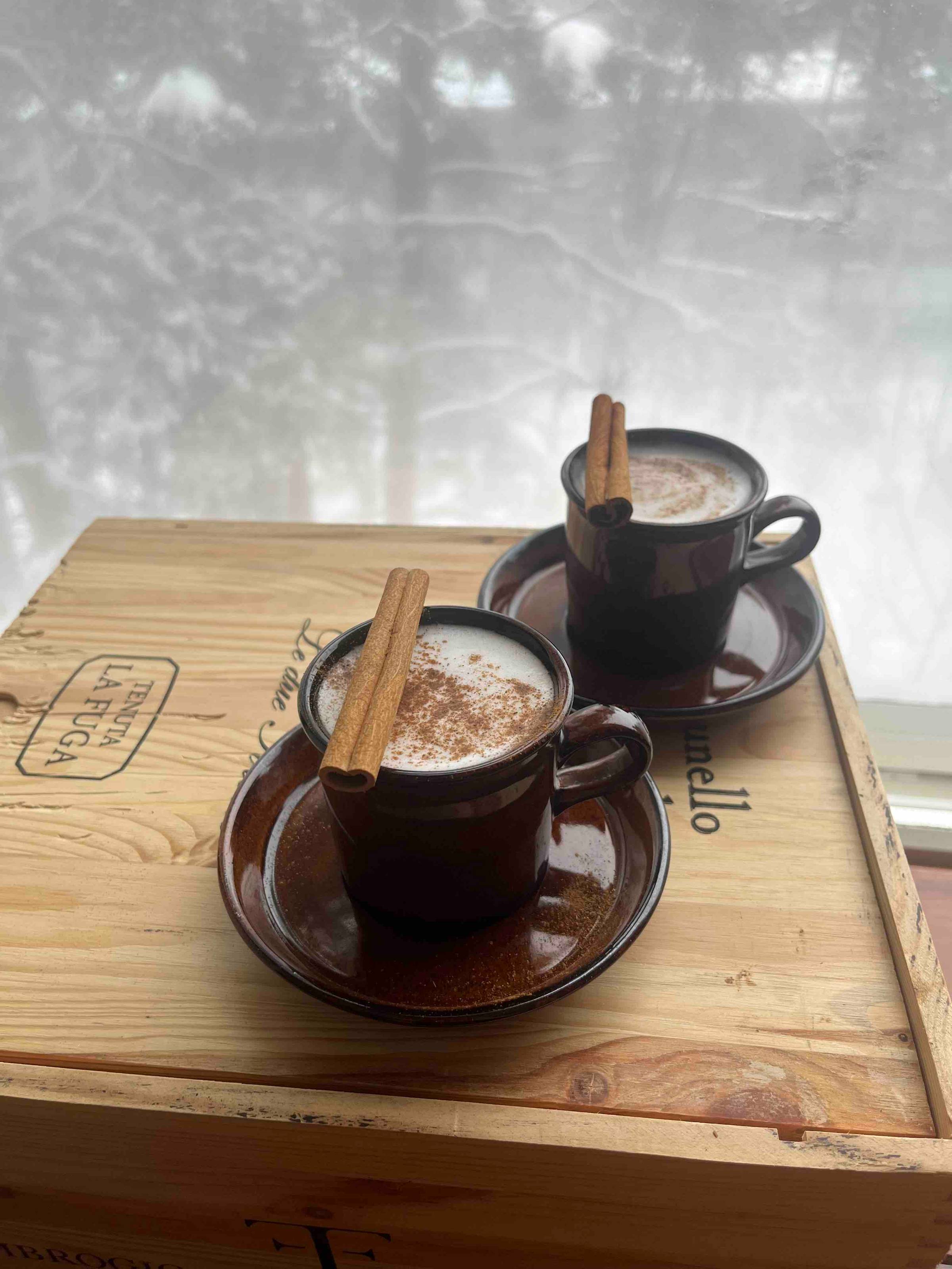 Two cups of rooibos chai latte with a cinnamon stick as garnish.