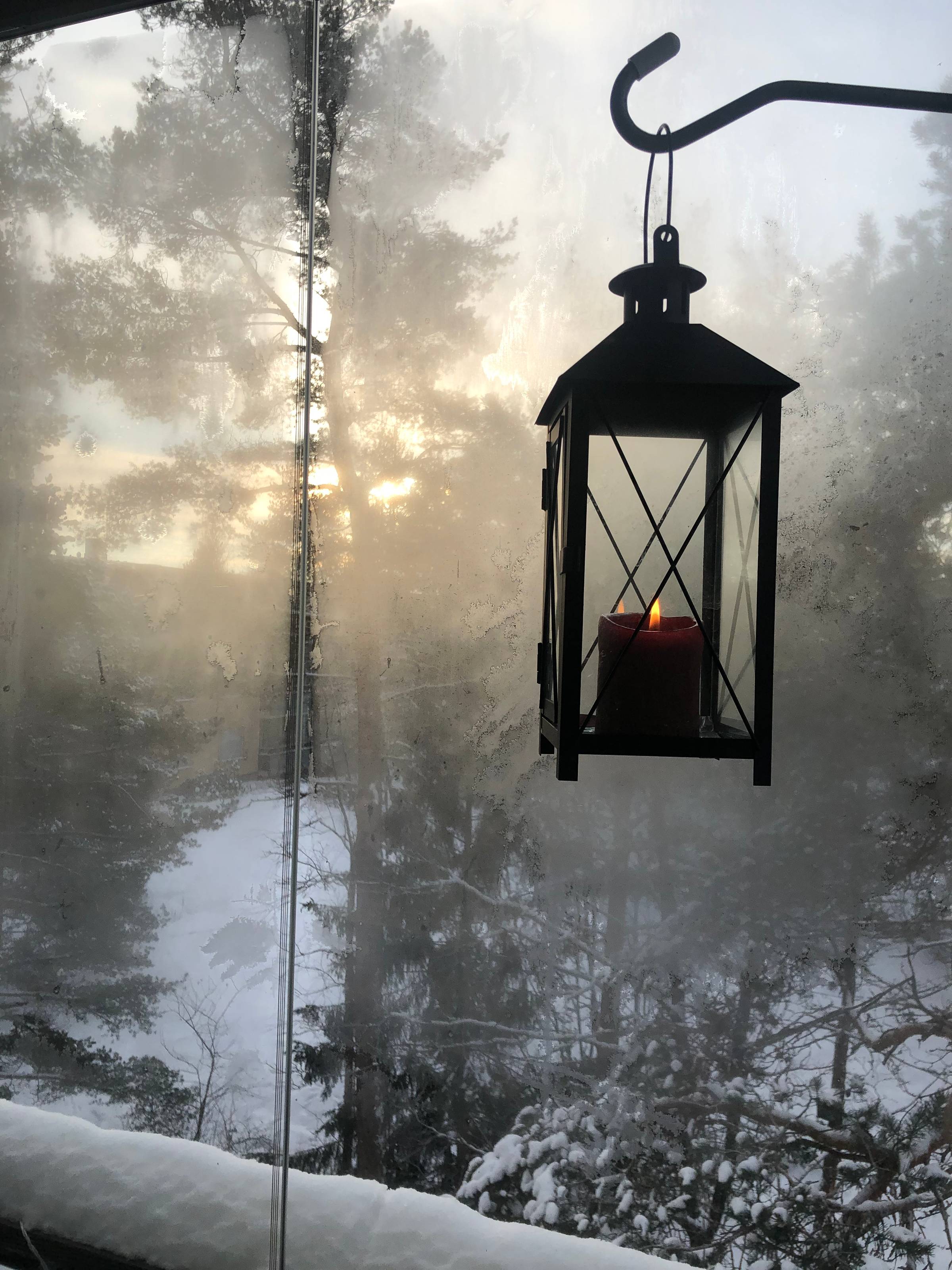A candle in the lantern in winter landscape.