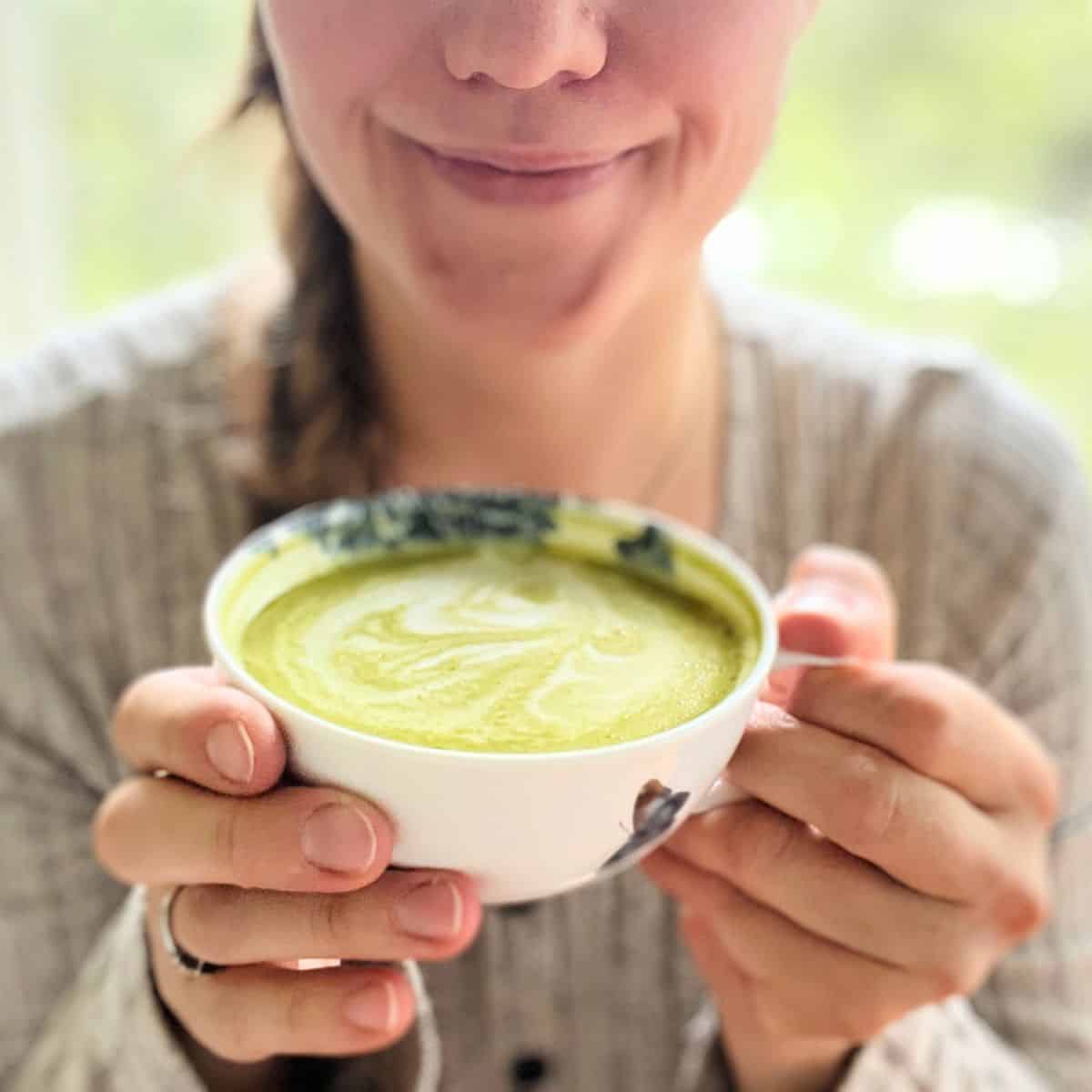 A woman holding a vanilla matcha latte cup in her hands
