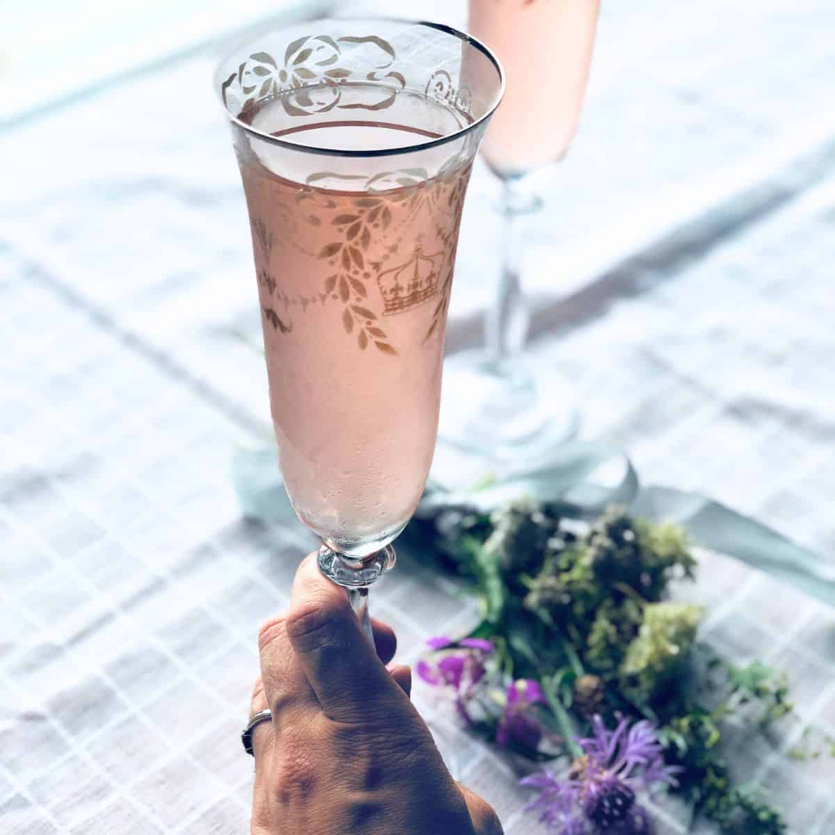 A woman holding a rhubarb juice in a flute glass