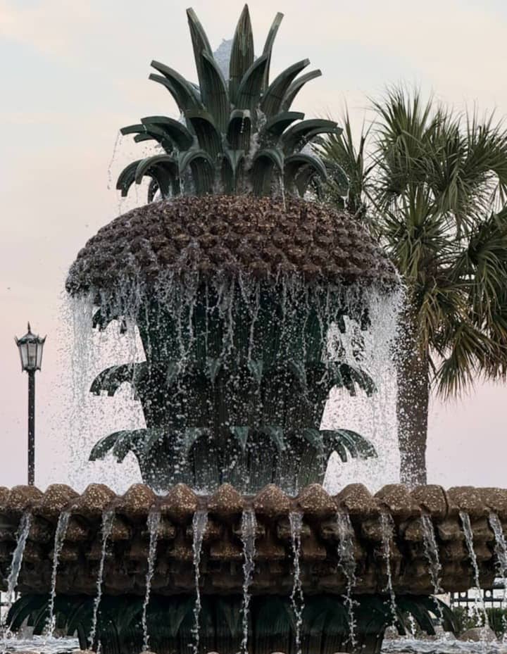 A pineapple fountain with water flowing over it.