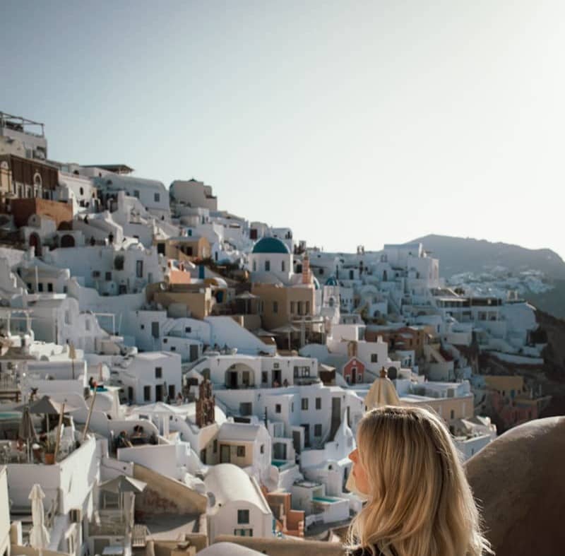 A woman standing on top of a hill next to a city