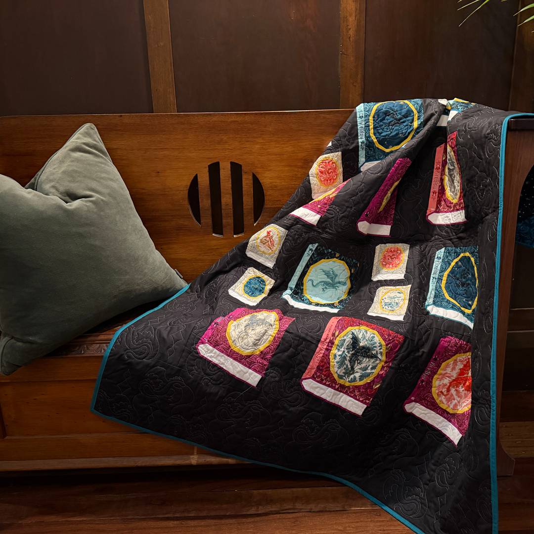 a moody photo of a book quilt draped across a wooden bench