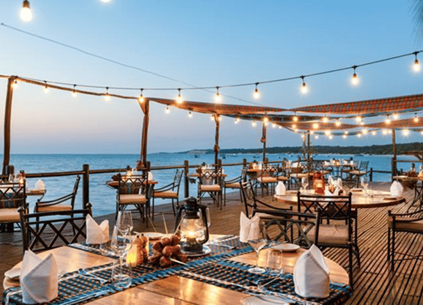 Terrace overlooking ocean with dinner tables and hanging lights