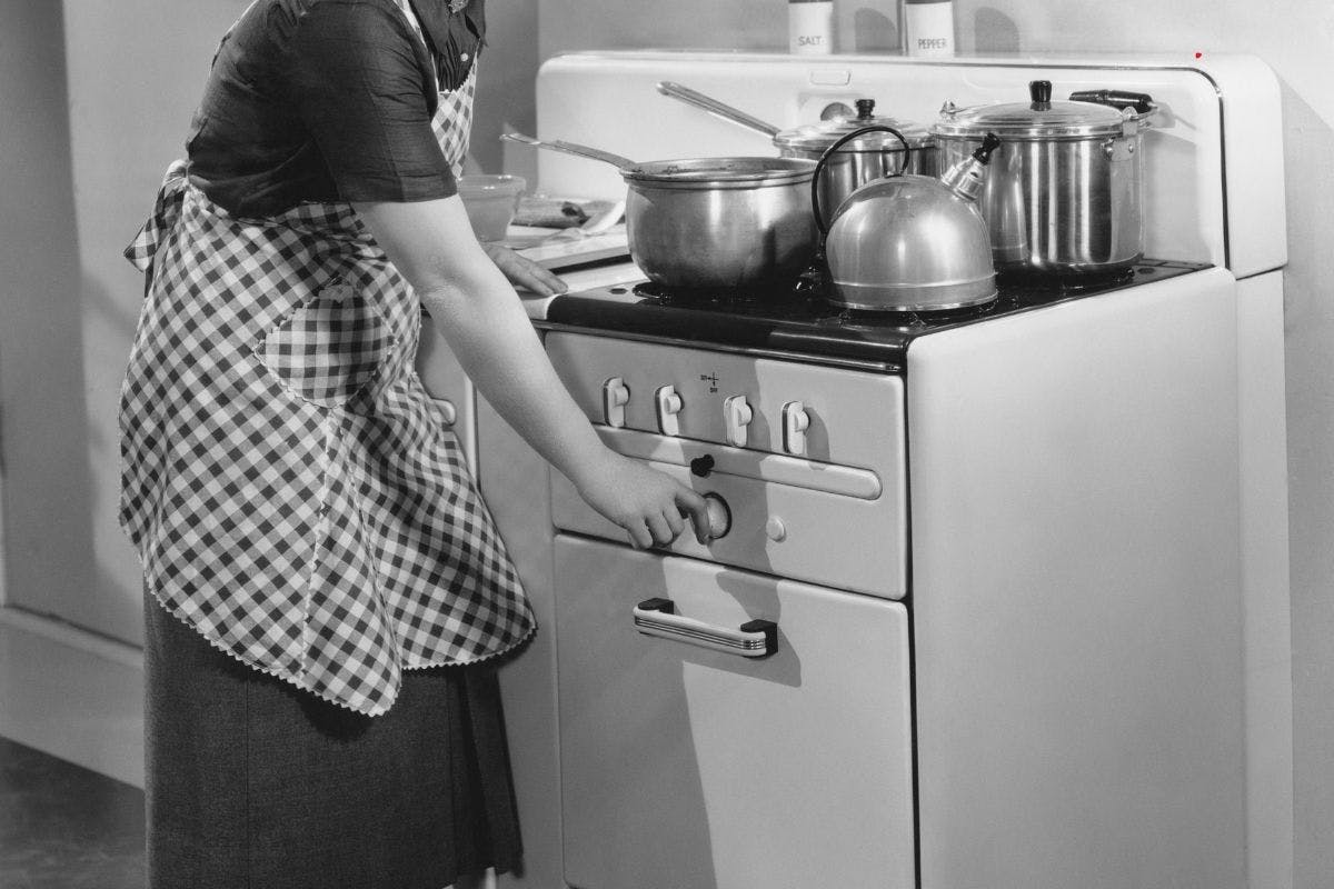 1930s housewife turning on oven