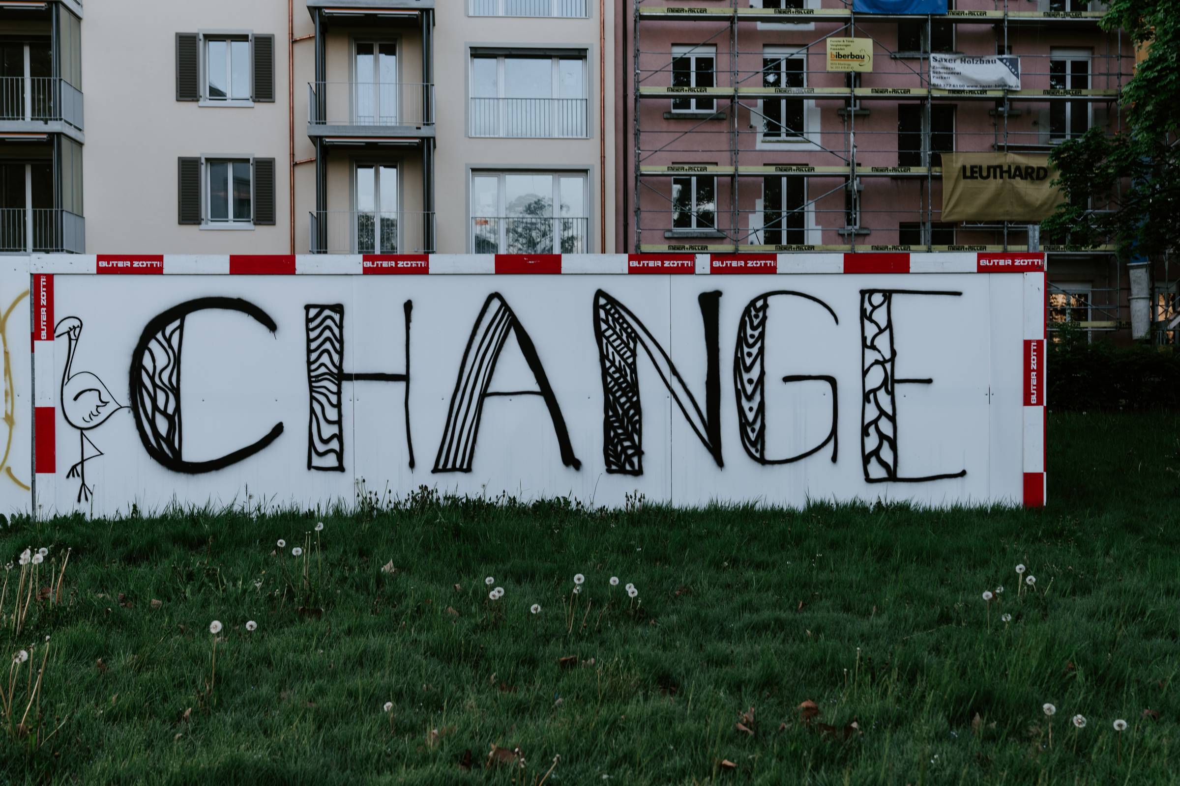 black grafitti of the word "change" on a white wall with the word