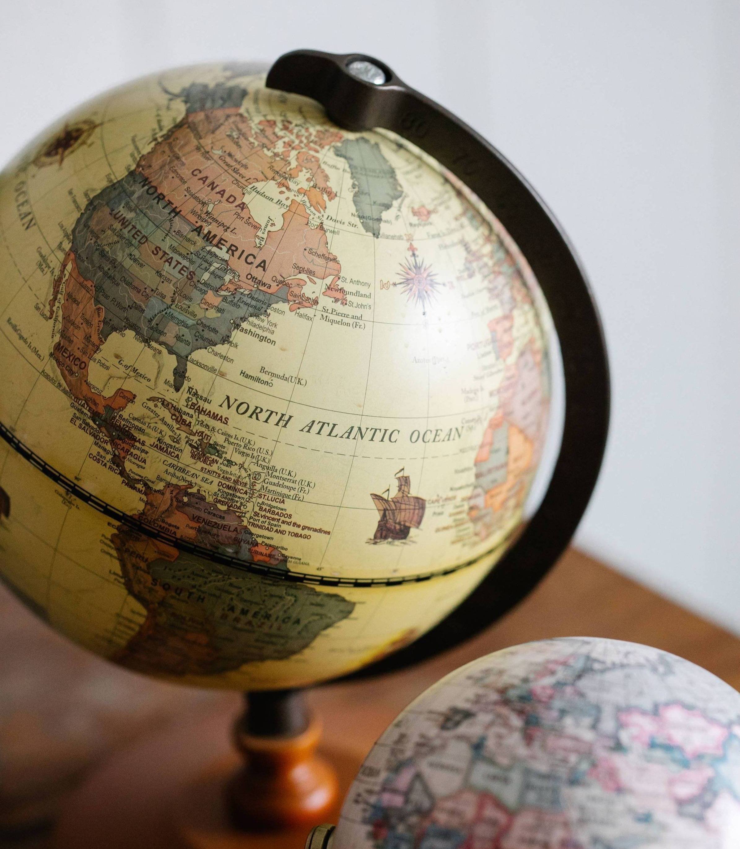 two globes sit on a wood table. 