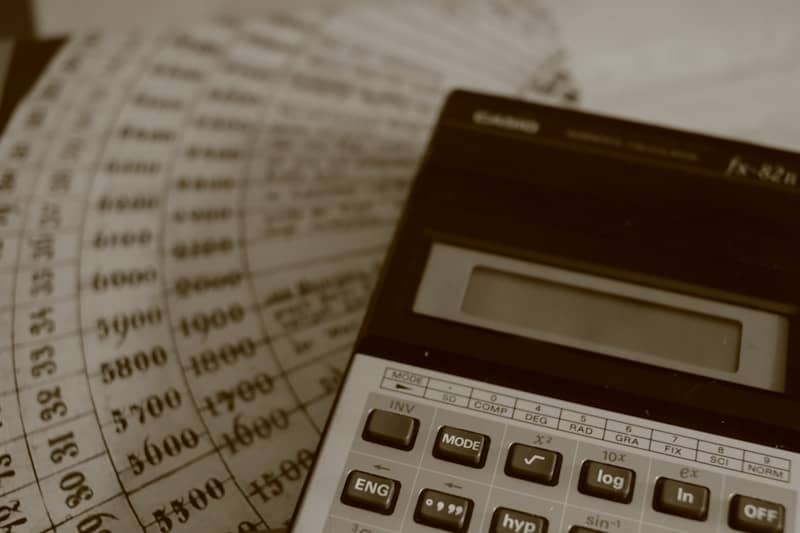A calculator rests on old financial ledger sheets with numbers.