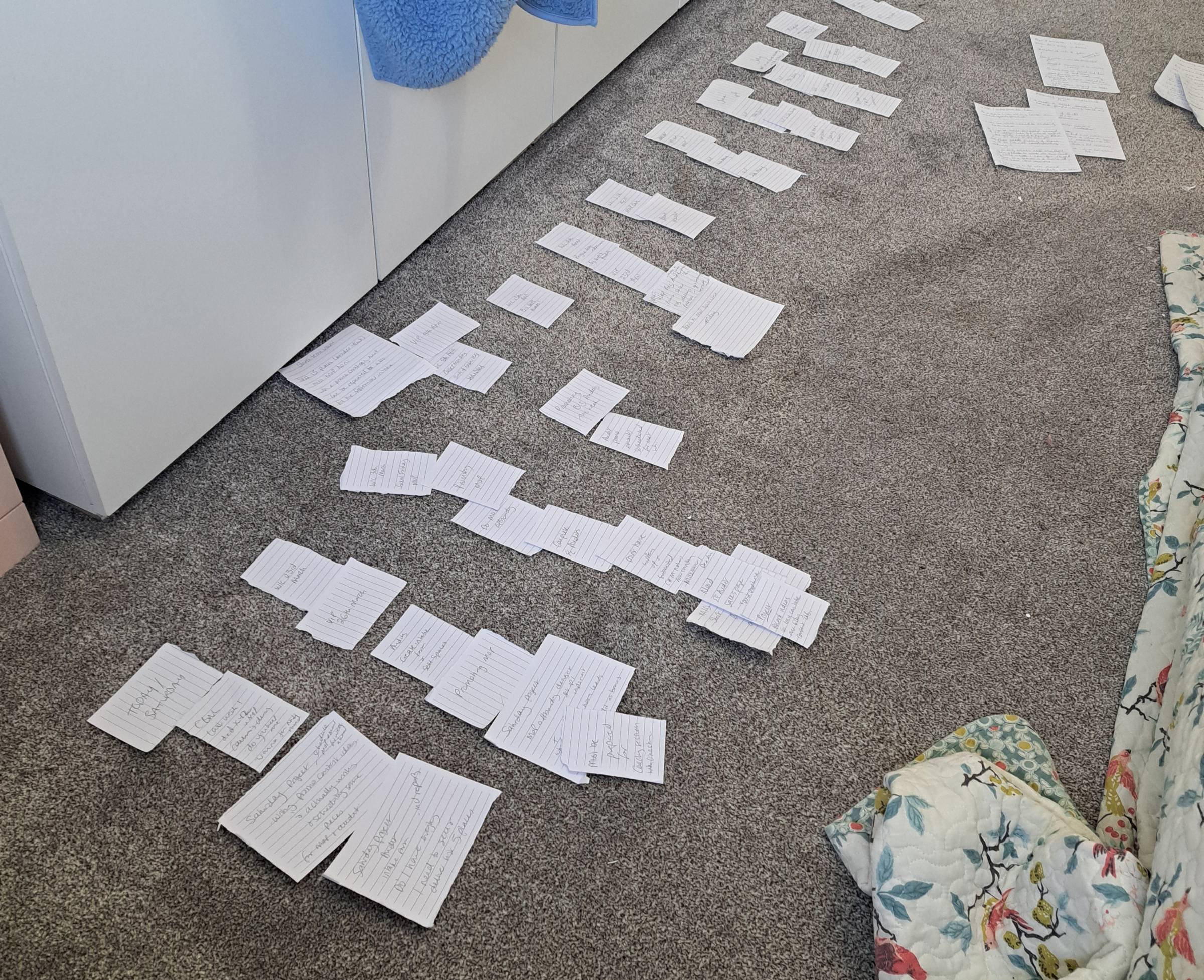 scraps of white paper arranged in columns on grey carpet