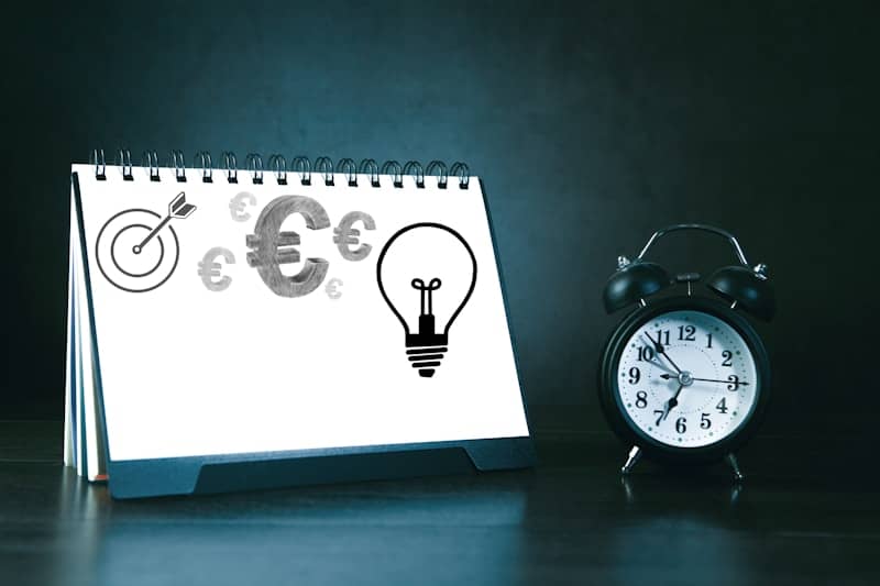 Desk calendar with business symbols and alarm clock.