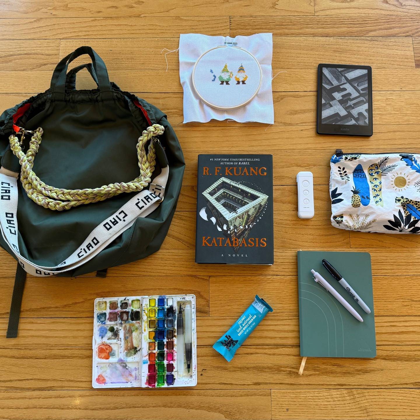 The analog bag trend is really just this:
carry things that help you think, read, and make. Here is what's in my @shopclarev Sac Tout Backpack at the moment, starting at the top: A two-thirds finished needlepoint project for my mother-in-law, my Kindle, an @alohacollection splash-proof pouch (side note, the medium size can fit a Kindle without a case), a small booklight/flashlight, journal and pens, a travel watercolor set, snacks, and the book Katabasis by @kuangrf. Links to these or similar items in bio, but I would love to know, what's in our analog bag right now?