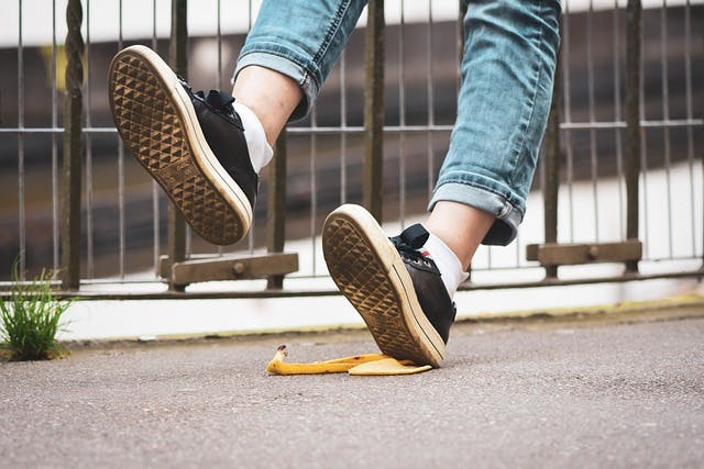 Person falling backwards after slipping on a banana peel in the street.