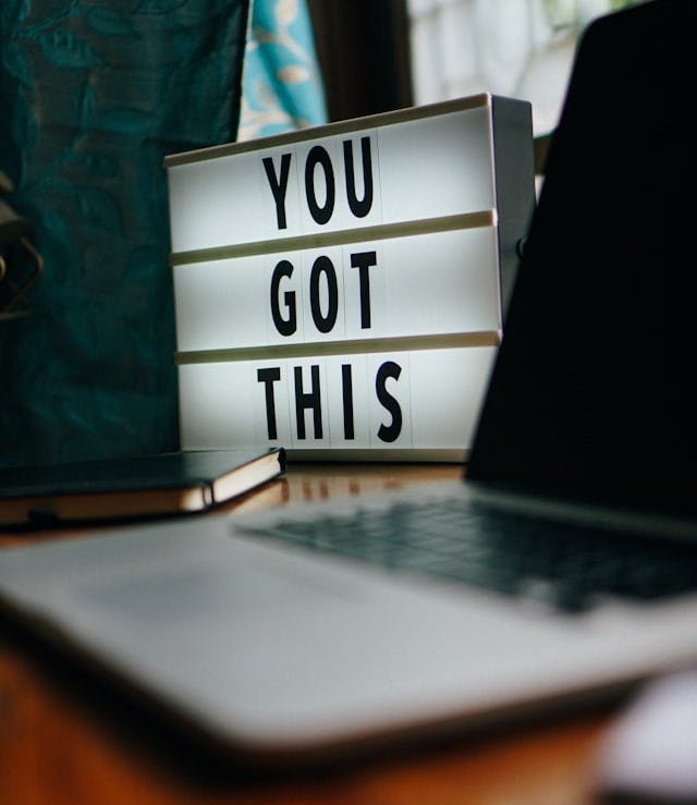 Board with the text "You got this" on a desk with a laptop in the foreground.