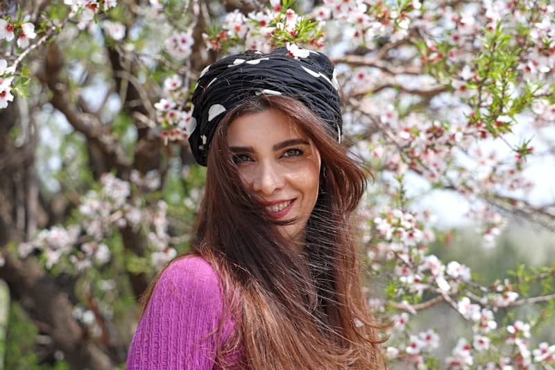 Woman smiling in front of blooming tree branches