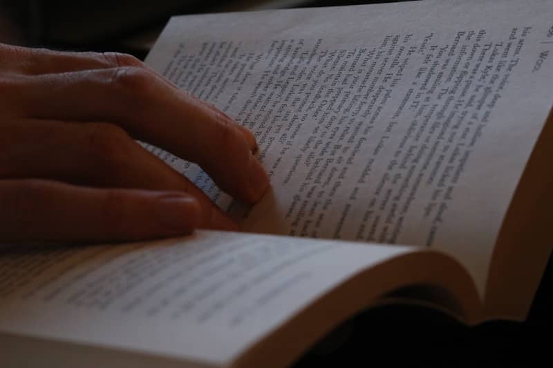 Fingers turning pages of an open book.