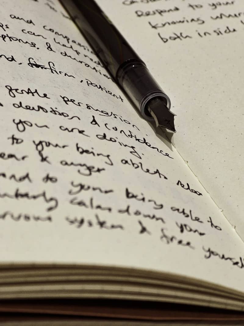 A fountain pen rests atop handwritten journal entries.