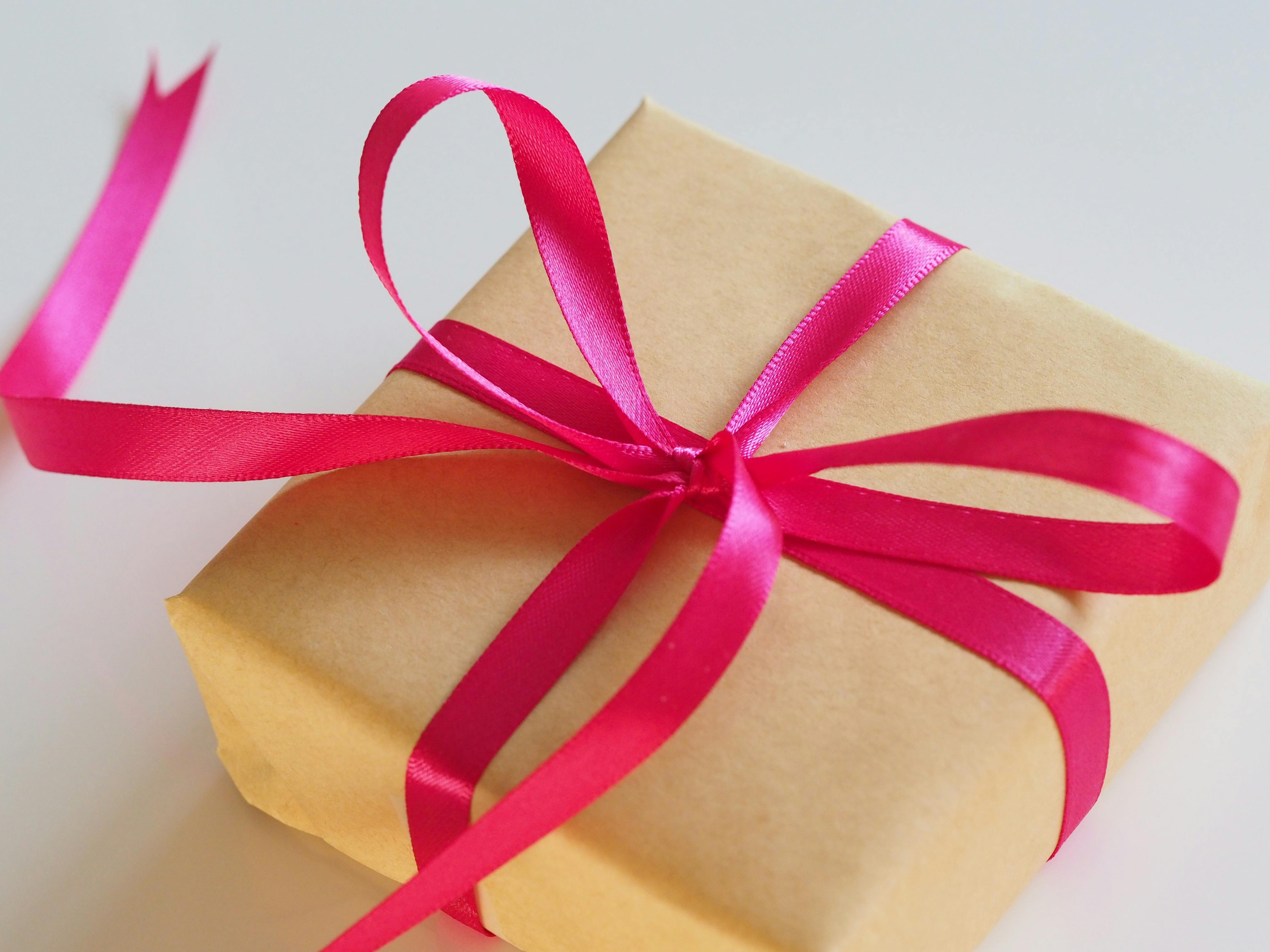 Photo of a present wrapped in brown paper with a pink ribbon.