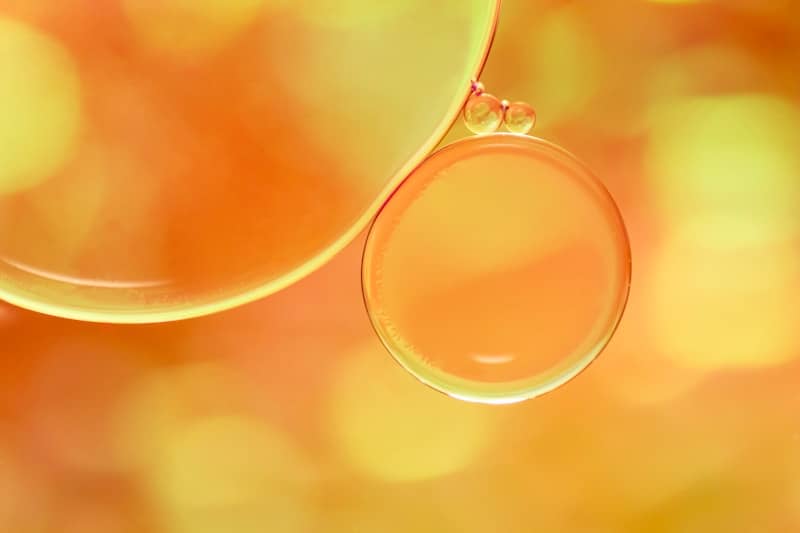 Macro view of orange oil droplets floating in a liquid with bokeh background
