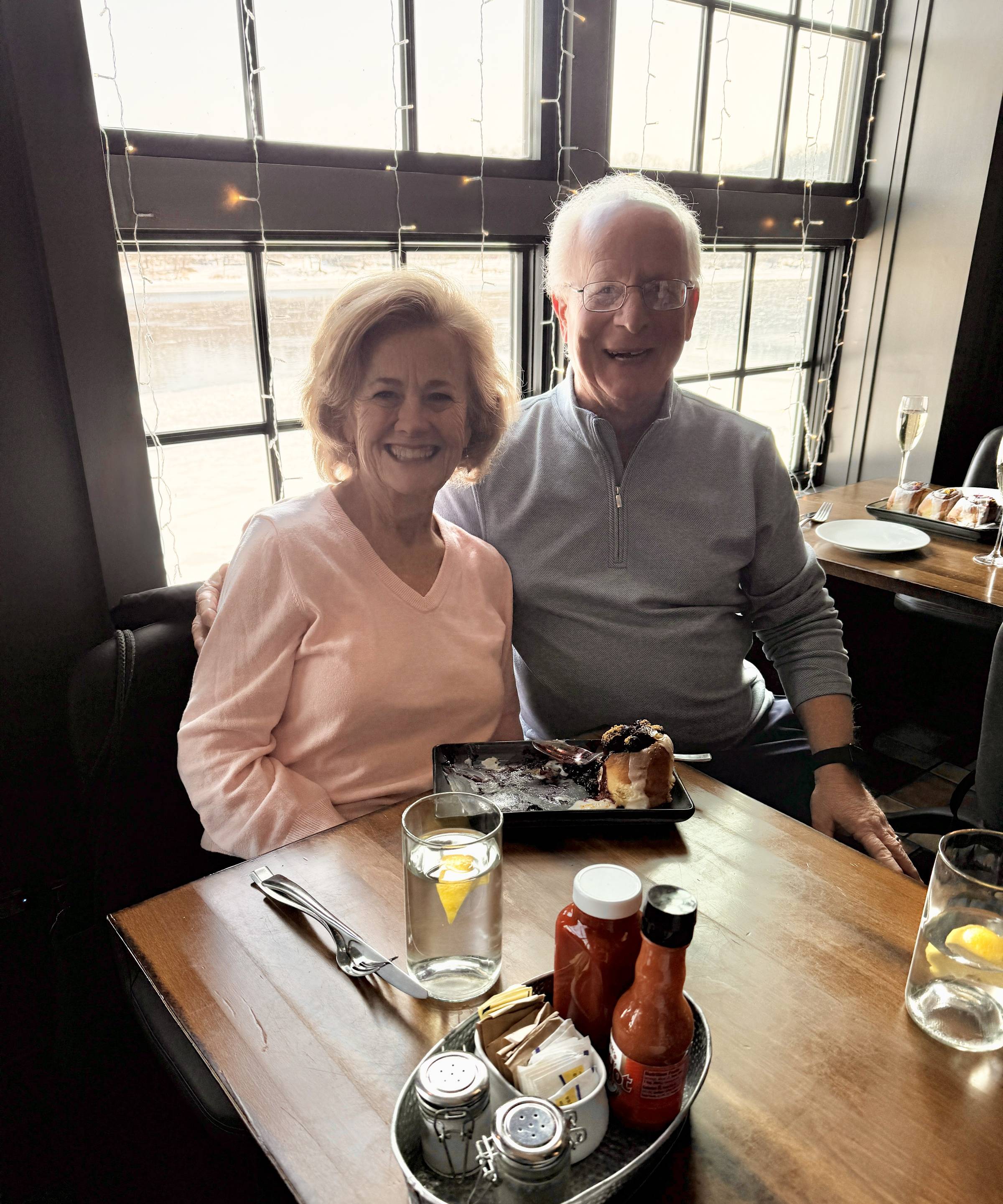 Couple smiling at a table inside Stella restaurant in New Hope, seated by a window with dessert and drinks in front of them.