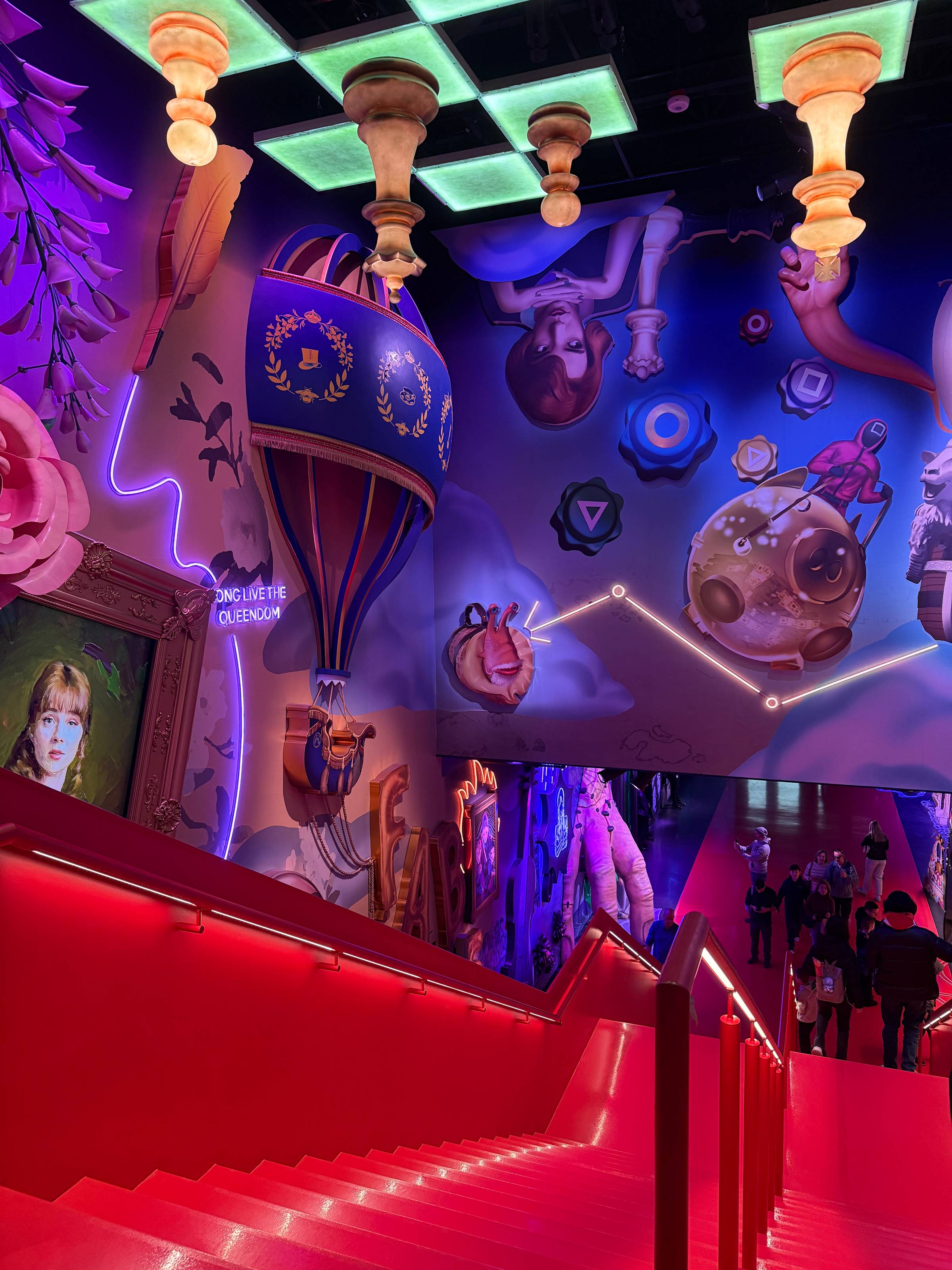 Red staircase at Netflix House leading to a lower level, surrounded by vibrant, themed wall art, neon accents, and immersive decorative elements.