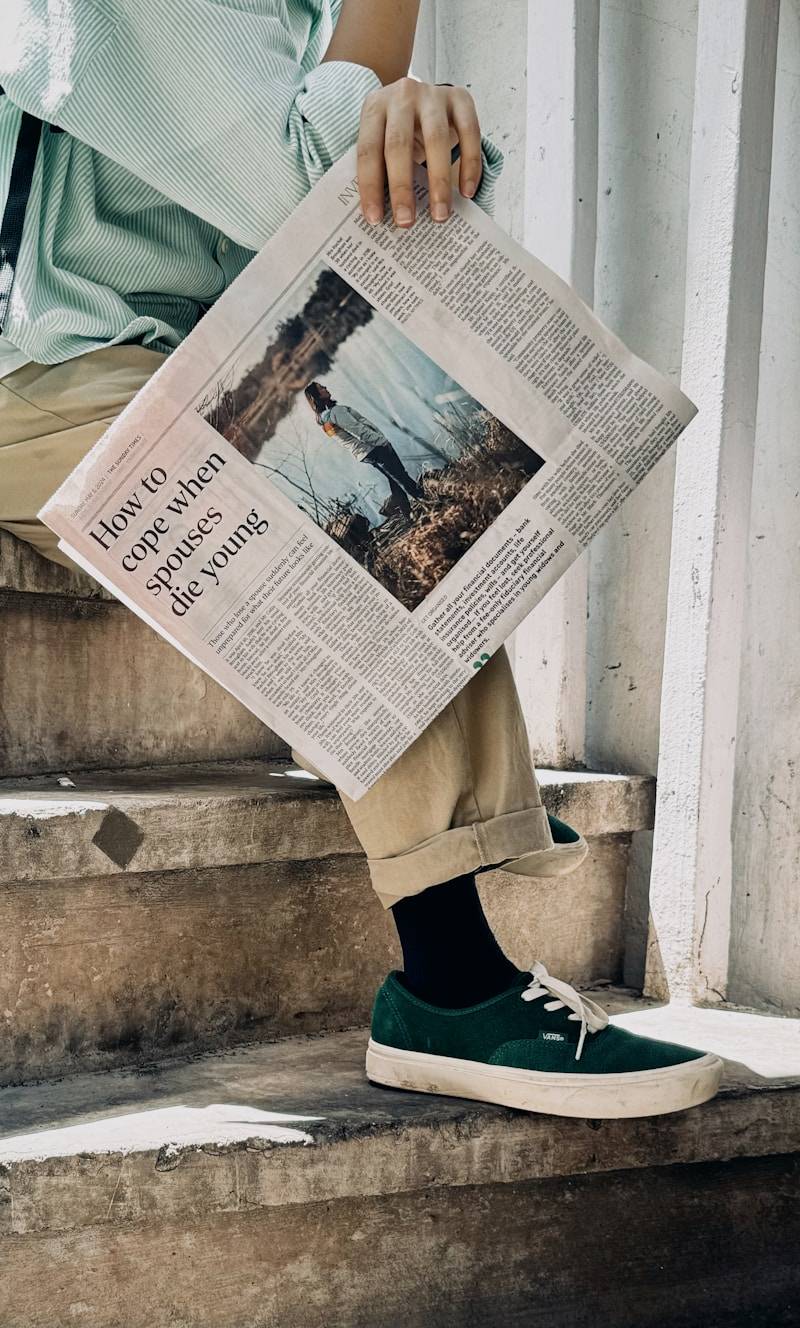 Person holding newspaper with headline about coping with loss.