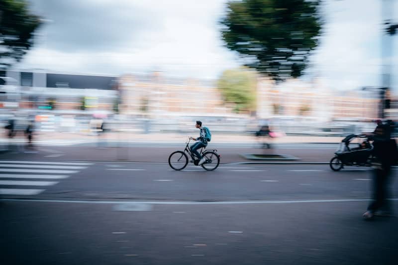 Cyclist rides through a blurred city street.
