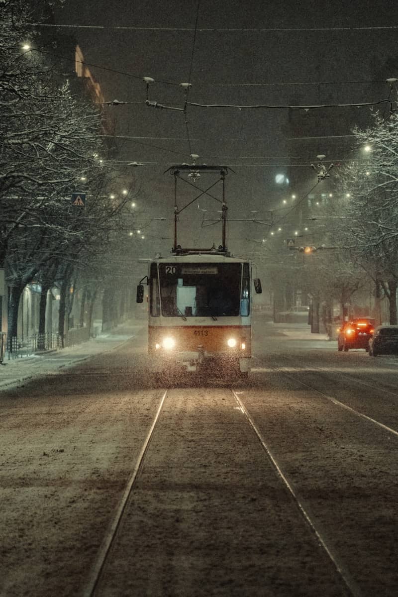 Tram driving on a snowy street at night