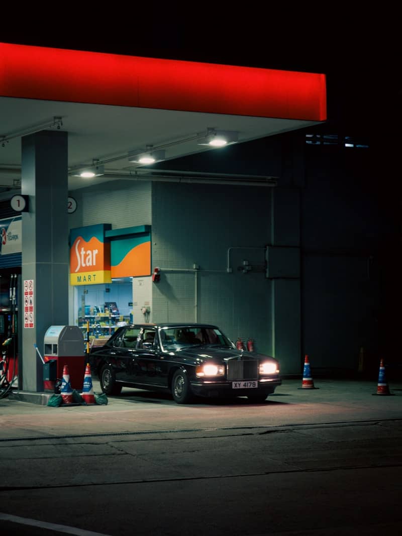 A black limousine parked at a gas station at night