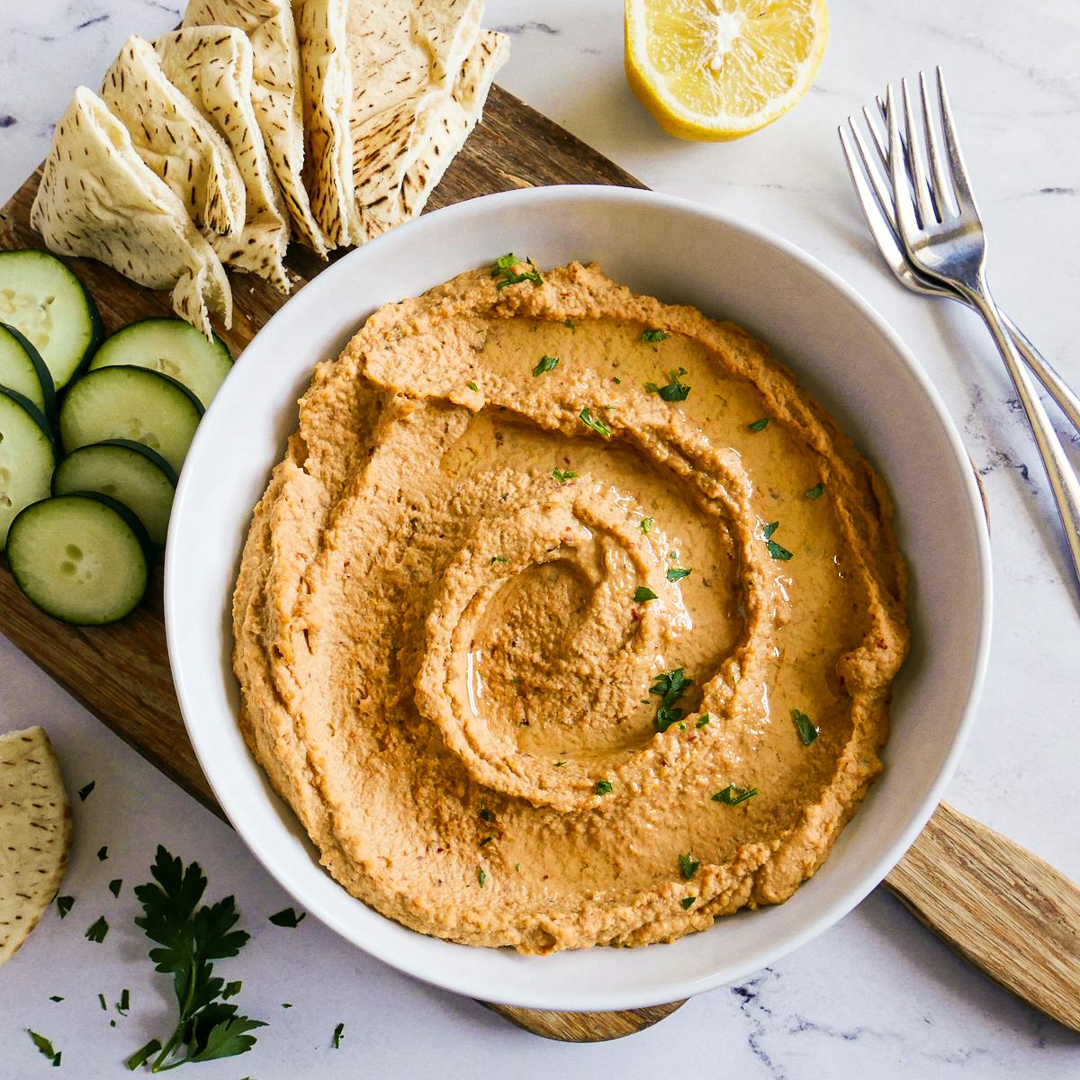 Bowl of spicy hummus garnished with olive oil and fresh parsley.