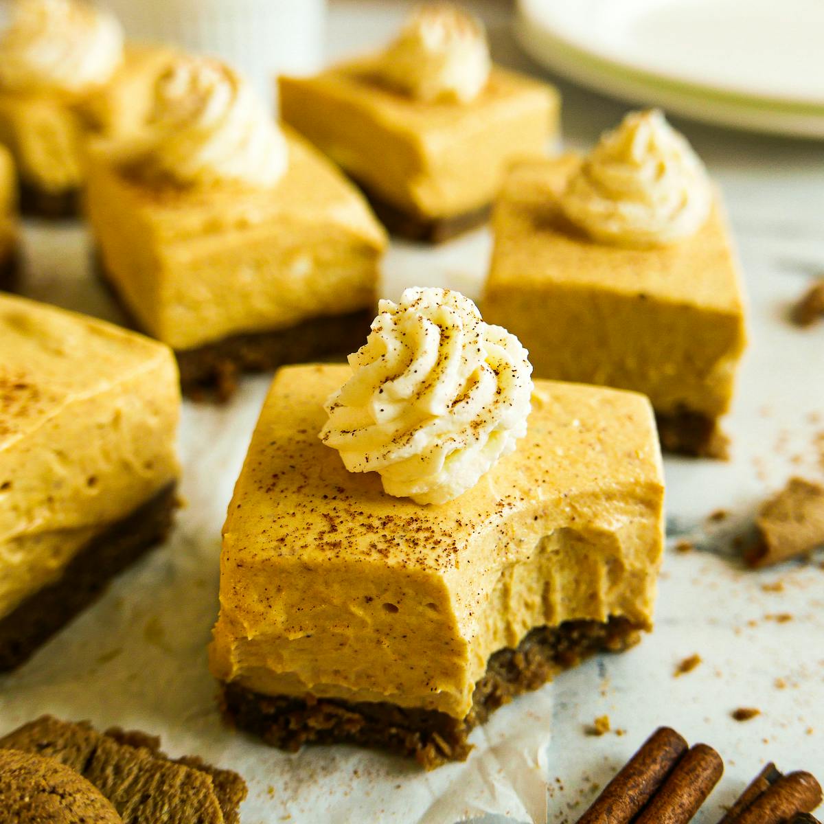 Pumpkin cheesecake bars arranged on parchment paper. 
