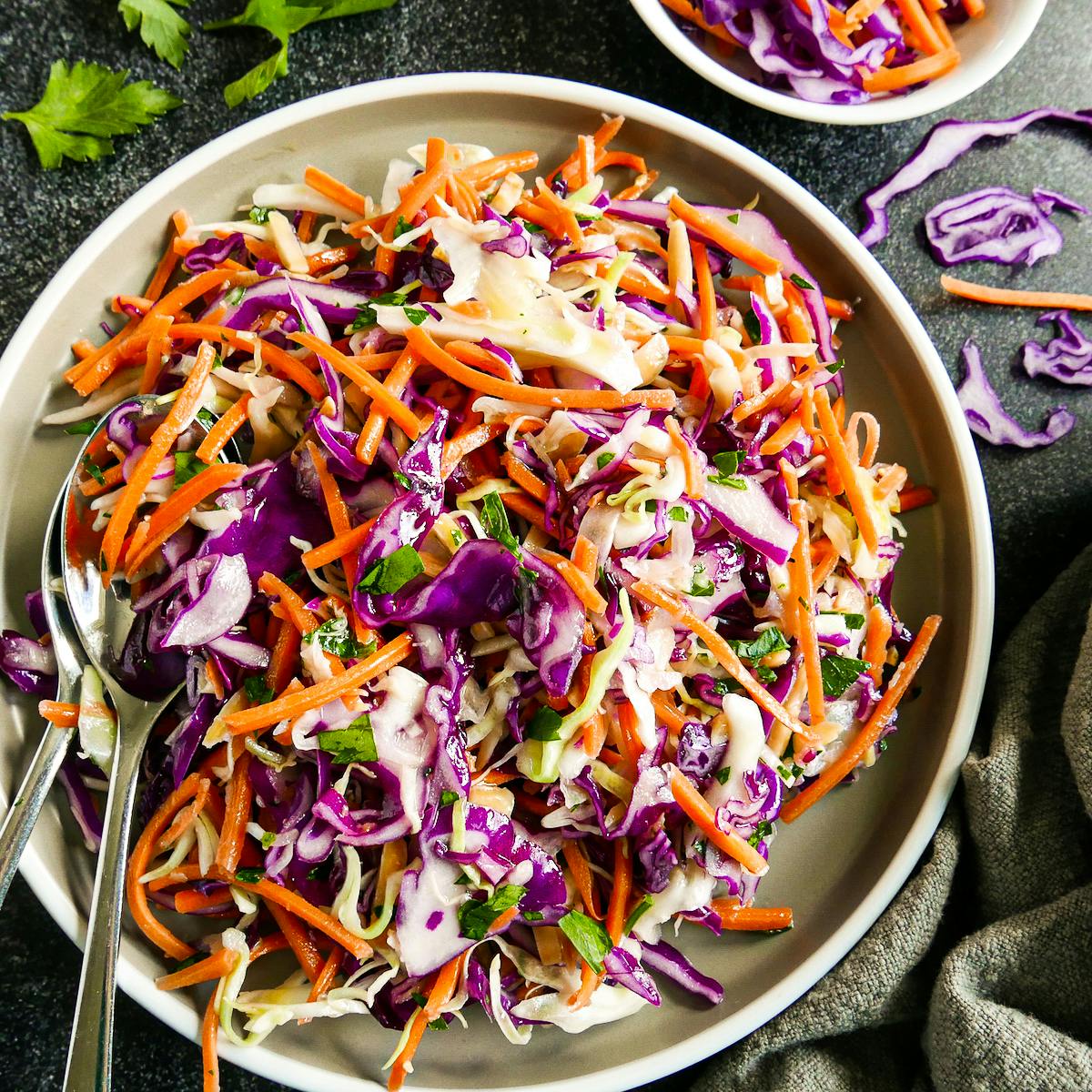 Plate of cabbage slaw with two forks and a napkin. 