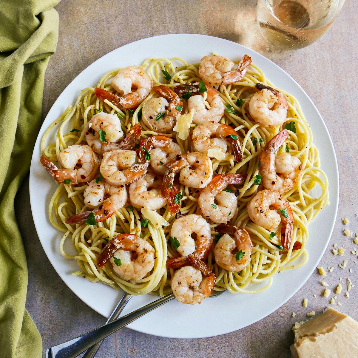 Plate of garlic shrimp spaghetti with a glass of white wine.
