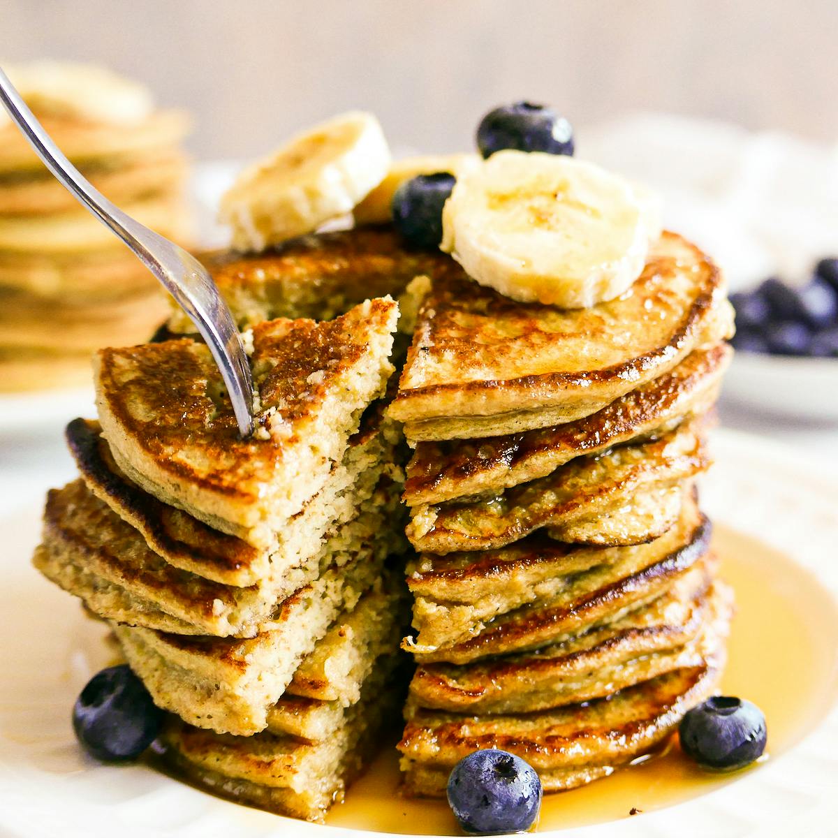 Stack of banana oat pancakes on a plate with syrup.