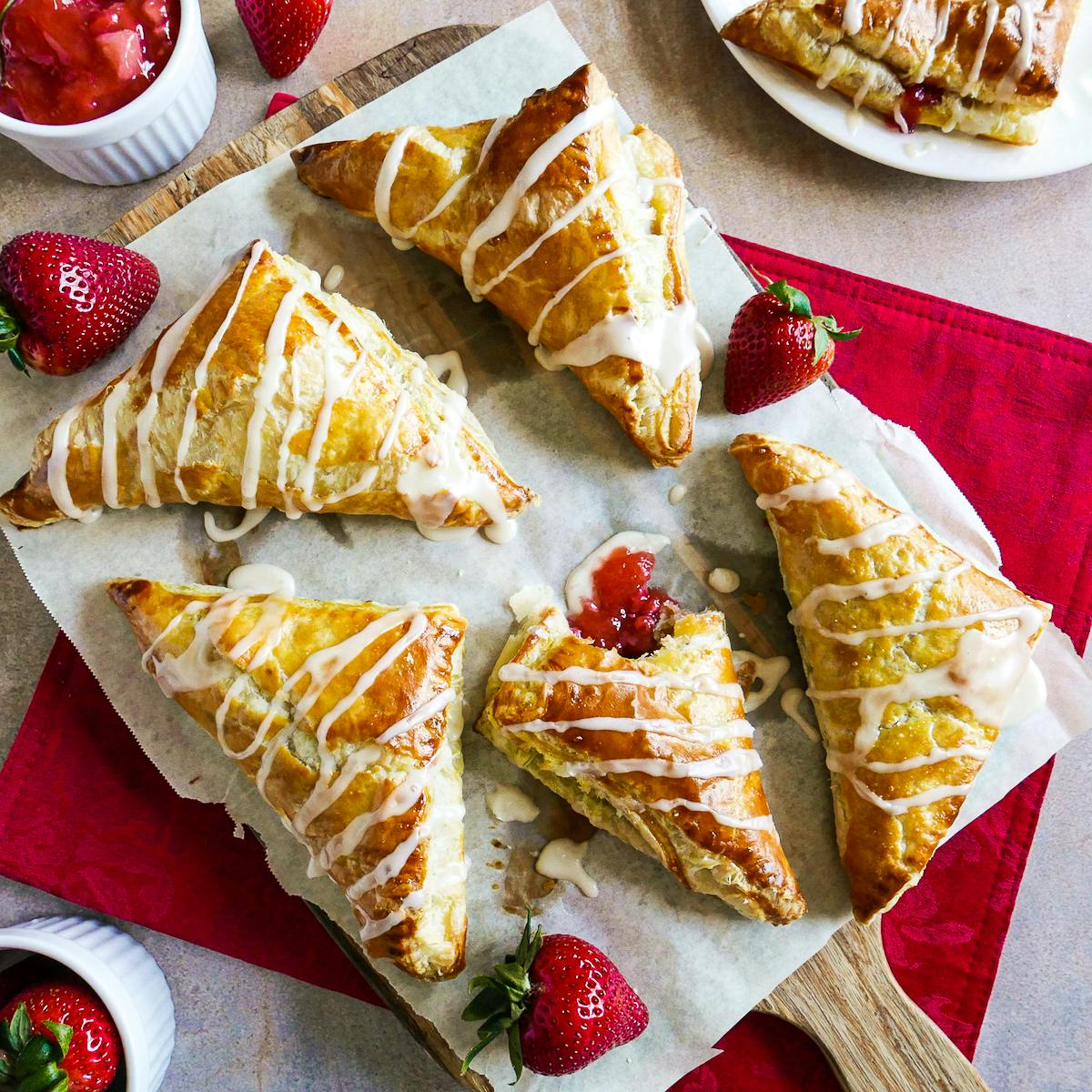 Five strawberry turnovers arranged on parchment paper.