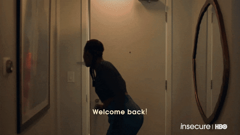 Gif of Issa Rae as Issa Dee opening her door to greet Amanda Seales as Tiffany, who holds a gift, on Insecure.