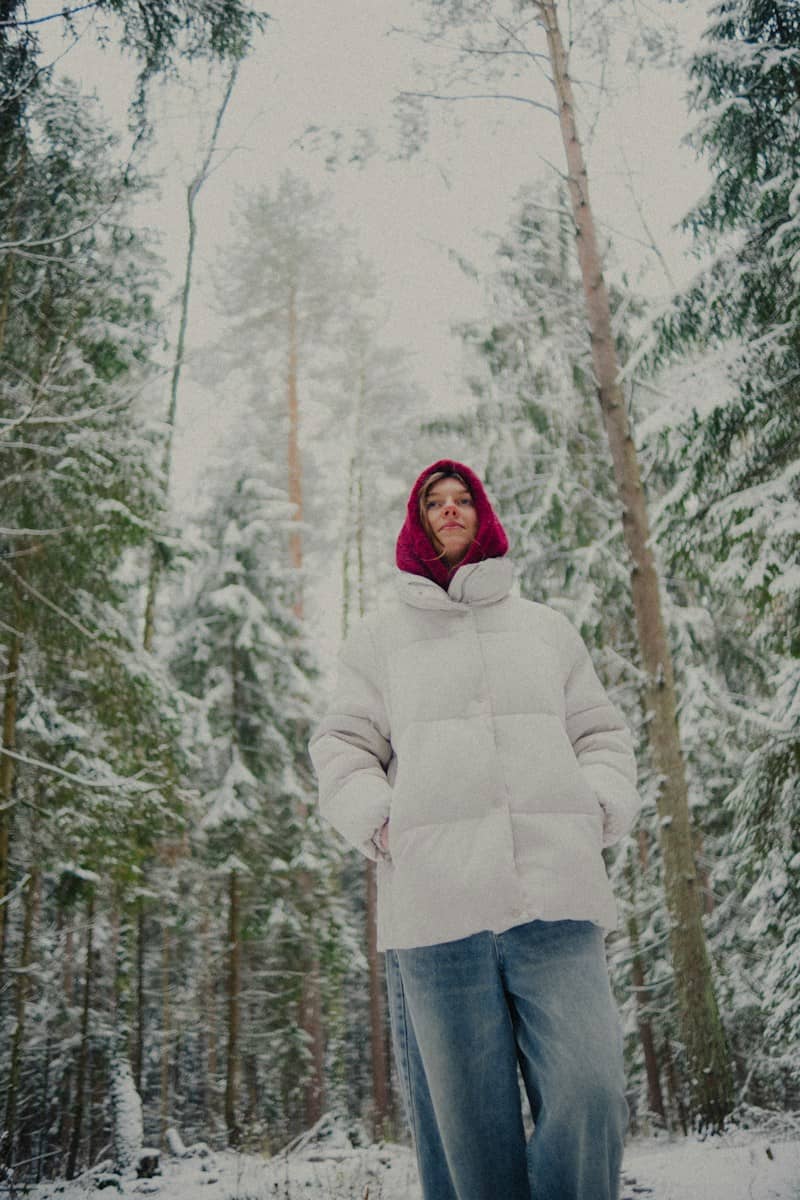 Woman in white puffer jacket in snowy forest