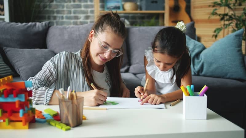 Woman and child drawing at a table.