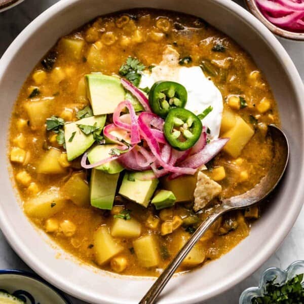 Mexican street corn soup with avocado on the top in a bowl