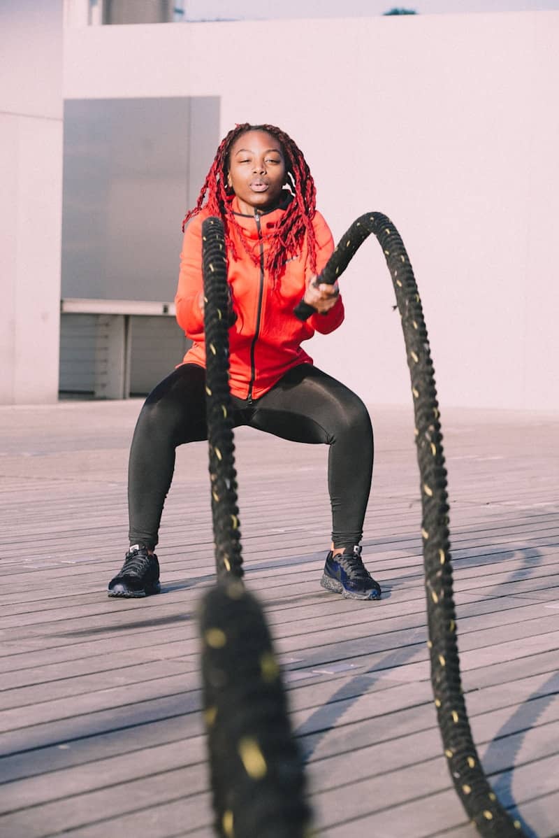 A woman in a red jacket is holding a black snake